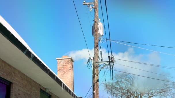 一个正方形的家庭烟囱就在一根电线杆旁边吸烟 那是无云的蓝天 — 图库视频影像