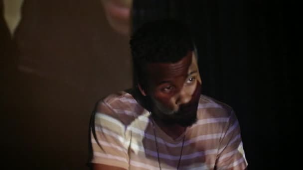アフリカ系アメリカ人男性がホームムービーをフラストレーションを持って見ている プロジェクターからの反射で — ストック動画