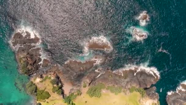 美しい岩の海岸 深い青色の海の水の上を横に飛んでいる空中ドローンの上からの眺め — ストック動画