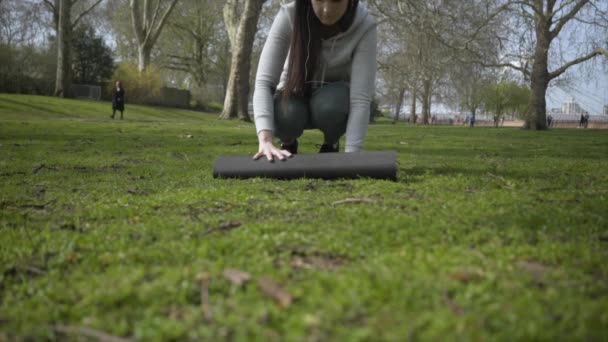 Caucasian Female Rolling Out Her Yoga Mat Park — Stock Video