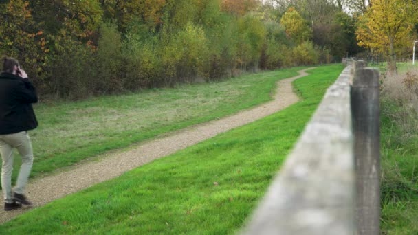 Чоловік Телефону Йде Вниз Ґрунтовій Доріжці Парку Подалі Від Камери — стокове відео