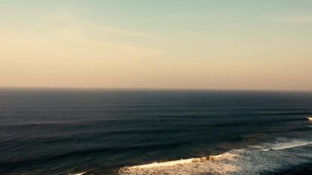 アフリカ南半球のブラフ上の深い青色の海で波を墜落させるビーチと海を見下ろす無人機で撮影された空中映像 — ストック動画