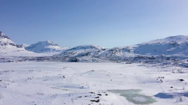 雪の山の風景の中に凍結湖で小さな町の空中ビュー — ストック動画