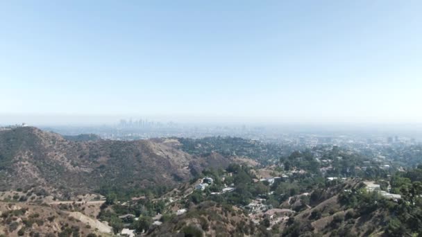 遠くにロサンゼルスと漠然とした風景を監督ハリウッドの丘の上に移動する高高度前方航空機 空は青く澄んでいて 晴れで暖かいです — ストック動画