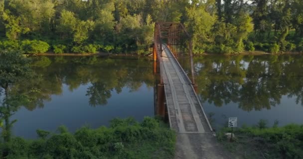 木の上の古い鉄の橋の右側の遅い航空トラックのショットに左暖かい午後の光の中で農村部の川並んで — ストック動画