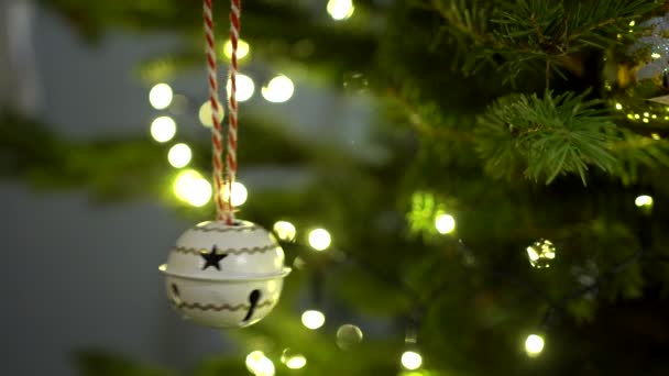 圣诞树上的装饰 圣诞钟声在一棵点亮的圣诞树上摇曳着 铃铛上挂着锯齿状的花纹 — 图库视频影像
