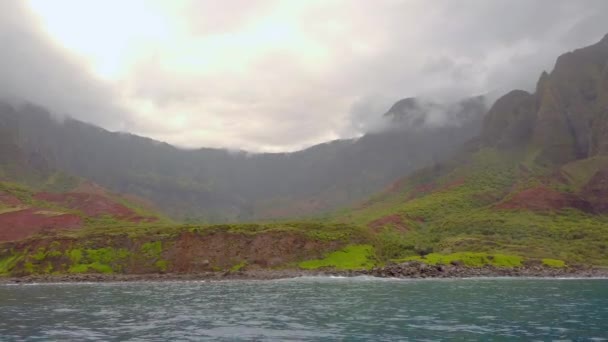 Hawaii Kauai波がNa Pali Coast State Wilderness Parkでクラッシュし 山の海岸線に向かって右側のパンにゆっくりと船に乗る — ストック動画