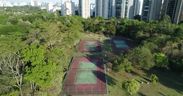公共公園のドローンと一緒に 4K解像度で スポーツ レジャー 自然と3つの美しいテニスコートに向かって前進 — ストック動画