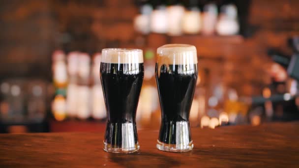 Barda Tezgahın Üstünde Köpükle Kaplı Iki Bardak Koyu Siyah Bira — Stok video