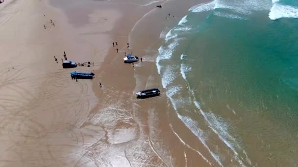 波からボートを引き 熱い砂のビーチに人々とトラックの滑らかな高いパノラマビュー — ストック動画