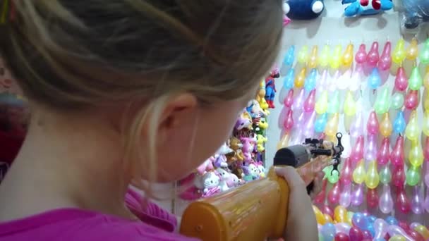 Young Caucasian Girl Shooting Rubber Bullet Gun Rows Colorful Balloons — Stock Video