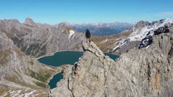 一个年轻人正在小心翼翼地走着 走到悬崖顶上 看到了瑞士卢内塞的壮丽景象 它下面是一个心形湖泊 爬上陡峭而危险的悬崖 — 图库视频影像