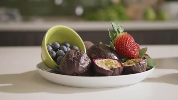 キッチンカウンターのボウルに新鮮な果物を用意しました パッションフルーツ ブルーベリー ストロベリー 健康的な食事4K — ストック動画