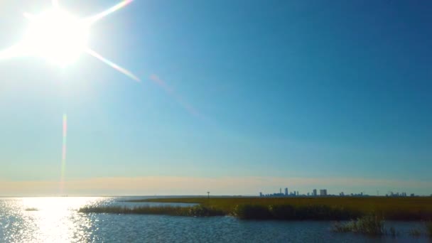 Hdは 4Kでも利用可能な素晴らしい晴れた日にフレームの右側に大西洋の都市のスカイラインと水路に明るい反射に過去の太陽を下に傾ける — ストック動画
