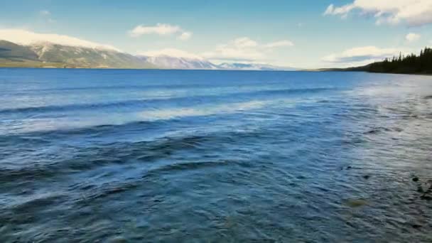 小さな波アトリン湖の海岸以上の洗浄 背景に白い山の峰 — ストック動画