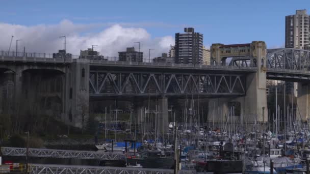 ボートドックを渡る橋と ウォーターフロントの街並みに停泊するマリーナの小さなボート高層ビルと背景にある橋を渡るパン — ストック動画