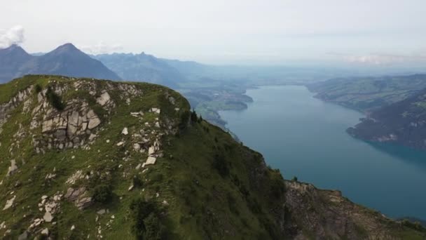 空中拍摄在瑞士莫根伯霍恩的山顶上循环 在远处的小村庄旁边 一条蓝色和绿松石的河流旁边露出陡峭而壮观的斜坡 — 图库视频影像