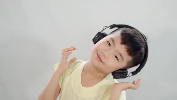 亚洲小孩一边用耳机听音乐 一边摇着头 — 图库视频影像