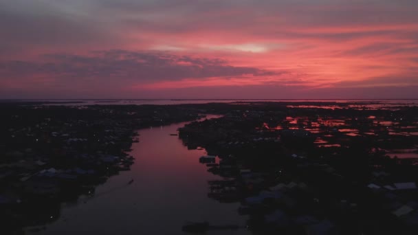 カンボジアのトンレサップ湖のほとりにある漁村の壮大な夕日の間に反射的な赤を育てる 川の入口の無人航空機 — ストック動画