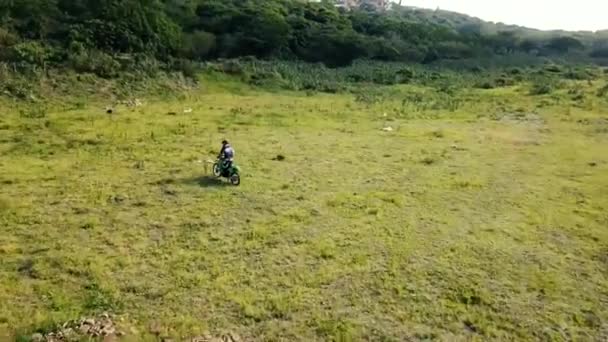 未舗装の区域内の緑のバイクに乗っている者は 上から後ろからドローンで道路を下りエンデューロ — ストック動画