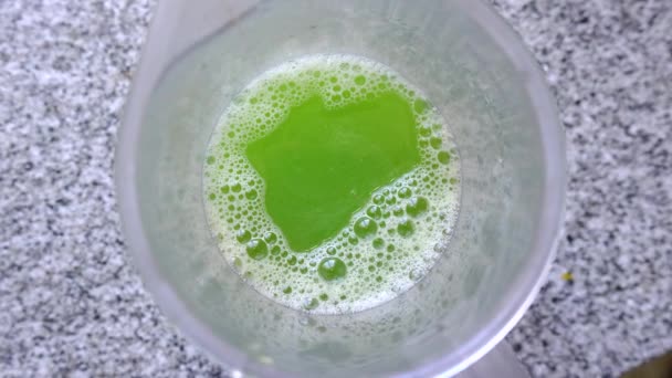 グラスの中の栄養価の高いグリーンジュースのトップビュー 頭上を回転して — ストック動画