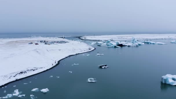 アイスランドの氷河湖の上空を飛行し ラグーンを横断する橋を背景に アイスランドの大氷河湖 — ストック動画