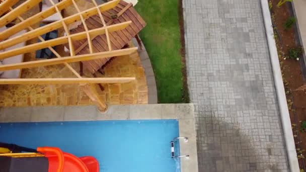 プールとウォータースライド付きの家の裏庭のドローンショット 逆ドリー傾き — ストック動画