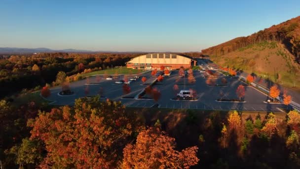 秋季落叶时山地一侧大型体育设施大楼及停车场的空中进路 — 图库视频影像