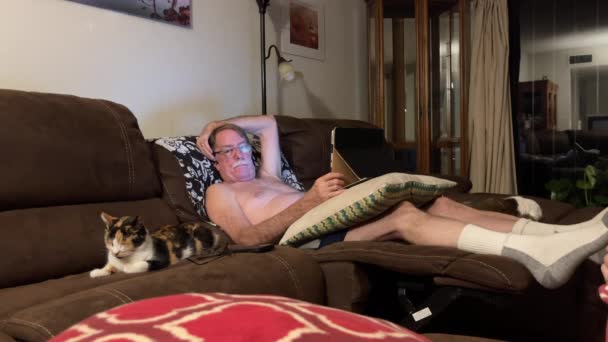Hemdloser Mann Sitzt Auf Couch Blickt Die Kamera Und Lächelt — Stockvideo