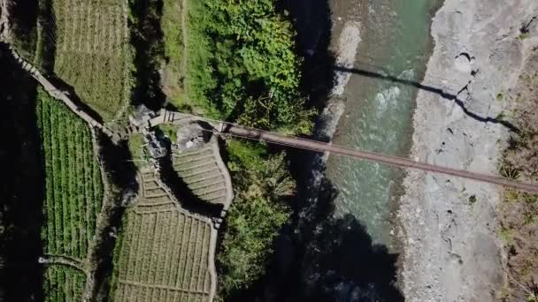 川上に架かる金属製の吊り橋で 晴れた日には農家の田んぼの庭の歩道につながります — ストック動画