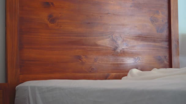 Zbliżenie Człowieka Ścielenie Łóżka Łóżko Drewnianym Zagłówkiem — Wideo stockowe