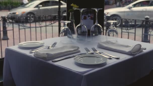 素敵なレストランでランチやディナーのためのダイニングテーブルセットウォーターストリートカフェセラミックプレート白いテーブルクロステーブルの上にナイフ布ナプキンをフォーク安定したスローモーションアプローチ — ストック動画