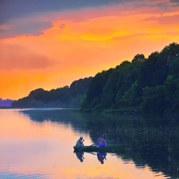 Silueta de pescadores sentados en barco en un lago . — Foto de Stock