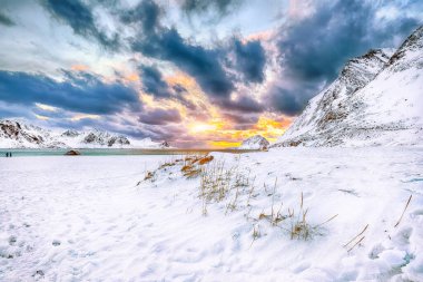 Gün batımında Haukland plajı ve Leknes yakınlarındaki karlı dağ zirveleriyle muhteşem bir kış manzarası. Konum: Leknes, Vestvagoy, Lofotens, Norveç
