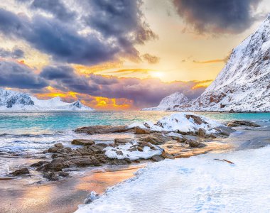 Gün batımında Haukland plajı ve Leknes yakınlarındaki karlı dağ zirveleriyle muhteşem bir kış manzarası. Konum: Leknes, Vestvagoy, Lofotens, Norveç