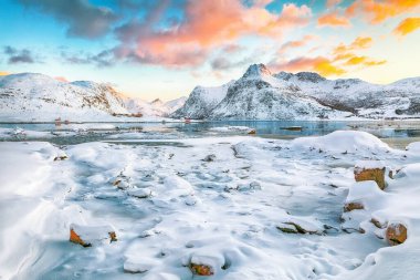 Güneş doğarken buzda çatlaklar olan muhteşem donmuş Flakstadpolen ve Boosen fiyortları ve Hustinden dağı arka planda. Konum: Flakstadoya Adası, Lofoten; Norveç, Avrupa