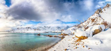 Küçük bir balıkçı köyünde çok kar ve Valberg yakınlarındaki karlı dağ zirveleriyle baş döndürücü bir kış manzarası. Konum: Valberg, Vestvagoy, Lofotens, Norveç