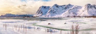 Gün batımında Vestvagoy adasında donmuş fiyortlu panoramik kış manzarası ve Valberg yakınlarında karlı dağ zirveleri. Konum: Valberg, Vestvagoy, Lofotens, Norveç