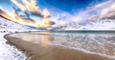 Gün batımında Vik sahilinin şaşırtıcı kış manzarası. Leknes yakınlarında çok kar ve karlı dağ zirveleri var. Konum: Leknes, Vestvagoy, Lofotens, Norveç