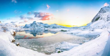 Güneş doğarken buzda çatlaklar olan muhteşem donmuş Flakstadpolen ve Boosen fiyortları ve Hustinden dağı arka planda. Konum: Flakstadoya Adası, Lofoten; Norveç, Avrupa