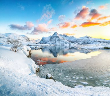 Fevkalade donmuş Flakstadpolen ve Boosen fiyortları ve gündoğumunda sudaki yansıma ve Hustinden dağı arka planda. Konum: Flakstadoya Adası, Lofoten; Norveç, Avrupa