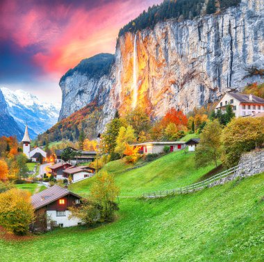 Gün batımında muhteşem Staubbach şelalesi ve İsviçre Alpleri ile Lauterbrunnen Vadisi 'nin büyüleyici sonbahar manzarası. Konum: Lauterbrunnen Köyü, Berner Oberland, İsviçre, Avrupa.