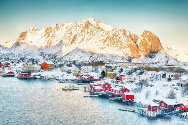Reine şehrinin dramatik akşam manzarası. Reinefjorden sahilinde kırmızı ajanlar var. Lofotens 'ta popüler bir seyahat yeri. Konum: Reine, Lofoten; Norveç, Avrupa