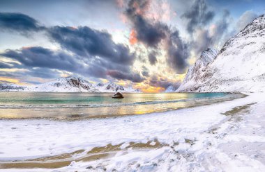 Güneş batarken Haukland sahilinin muhteşem kış manzarası. Leknes yakınlarında çok kar ve karlı dağ zirveleri var. Konum: Leknes, Vestvagoy, Lofotens, Norveç