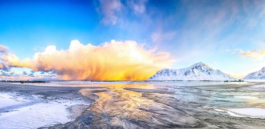 Skagsanden plajında güneş doğarken parlayan bulutlarla muhteşem bir kış manzarası. Popüler turizm merkezi. Konum: Flakstadoya Adası, Lofoten; Norveç, Avrupa