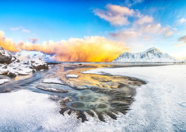 Skagsanden sahilinde güneş doğarken parlayan bulutlarla birlikte inanılmaz bir kış manzarası. Popüler turizm merkezi. Konum: Flakstadoya Adası, Lofoten; Norveç, Avrupa