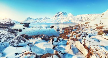 Moskenesoya ve Flakstadoya adalarını ayıran Sundstraumen Boğazı 'nın olağanüstü kış manzarası. Kayalık kıyı şeridi çatlamış buzla kaplı. Konum: Flakstadoya Adası Lofoten; Norveç, Avrupa