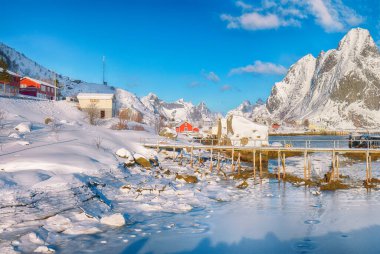 Reine Köyü 'ndeki muhteşem kış güneşli manzarası ve Gravdalbukta Körfezi' nin üzerindeki kırık buzlu yaya köprüsü. Konum: Reine, Lofoten; Norveç, Avrupa