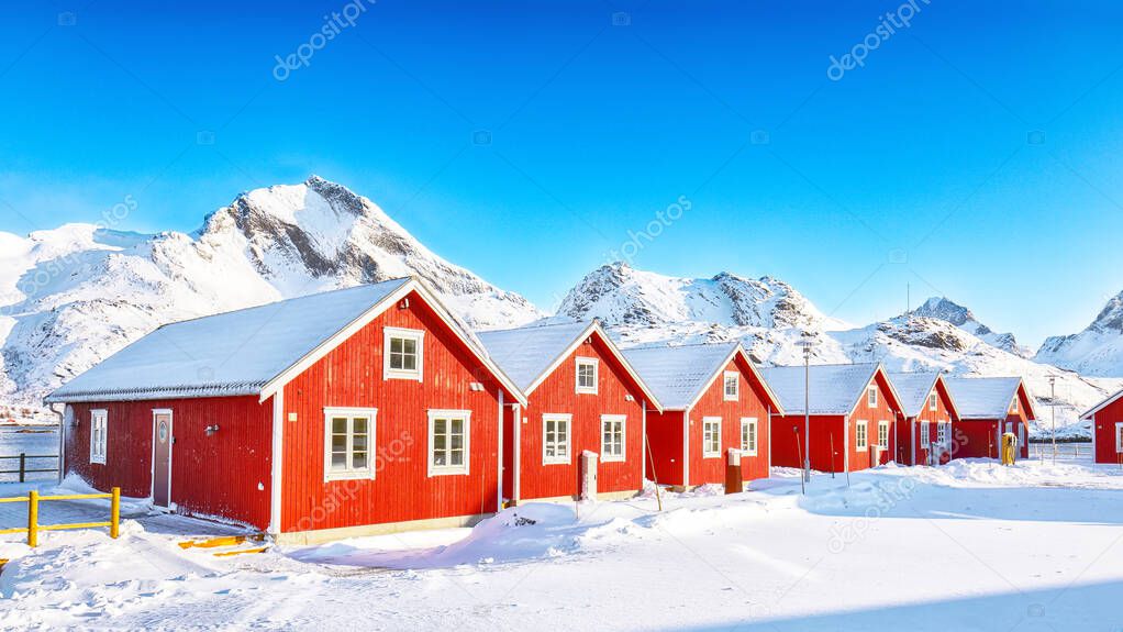 Astonishing winter scenery with traditional Norwegian red wooden houses on the shore of  Sundstraumen strait  that separates Moskenesoya and Flakstadoya islands. Location: Flakstadoya island, Lofoten; Norway, Europe