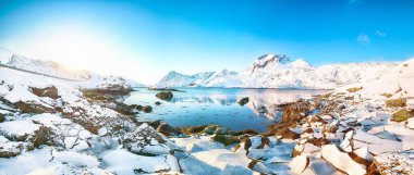 Moskenesoya ve Flakstadoya adalarını birbirinden ayıran Sundstraumen Boğazı 'ndaki muhteşem kış manzarası. Kayalık kıyı şeridi çatlamış buzla kaplı. Konum: Flakstadoya Adası Lofoten; Norveç, Avrupa